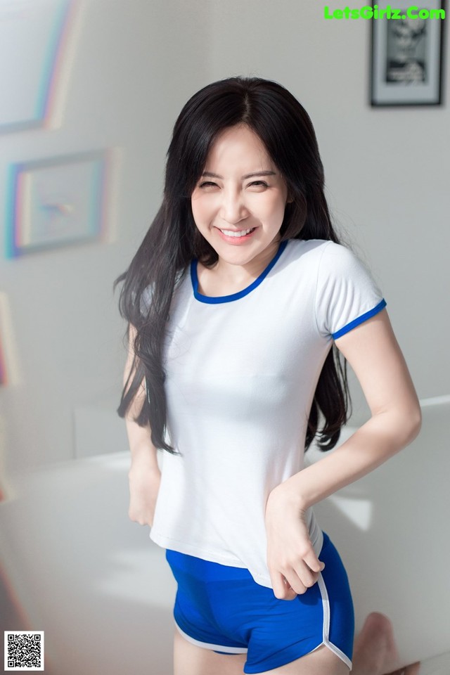 A woman in a white shirt and blue shorts posing for a picture.
