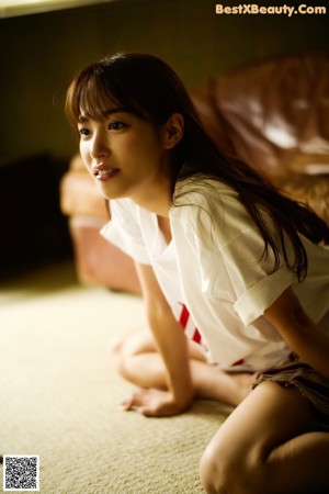 A naked woman sitting on a couch with her legs crossed.