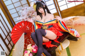 A woman in a red and yellow kimono sitting on a table.