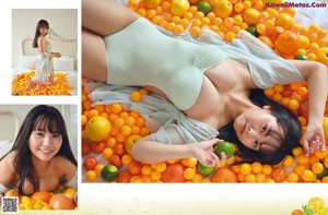 A woman laying on top of a pile of oranges.