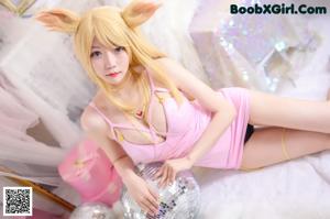 A woman in a bunny costume sitting on a bed with a disco ball.