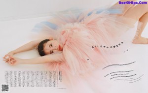 A woman in a pink tutu laying on a white surface.