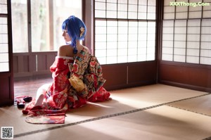 A woman in a red kimono sitting on a chair.