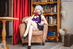 A woman sitting on a chair in front of a book shelf.
