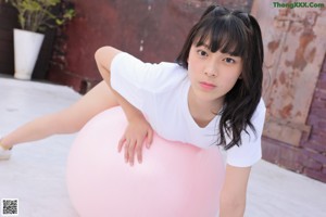 A woman crouching down holding a water gun in her hand.
