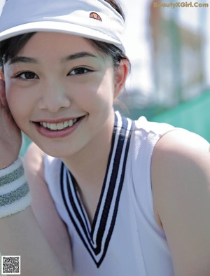A young woman wearing a white tennis outfit and a white hat.