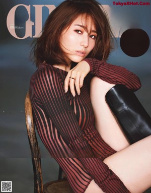 A woman in a purple sweater and black pants posing for a magazine.