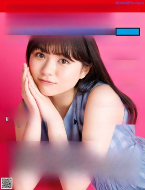 A woman with long black hair and bangs is posing for a magazine.