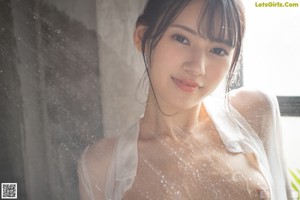 A woman in a white shirt and gray panties posing for the camera.