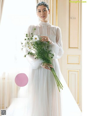 A woman in a wedding dress with a ring on her finger.